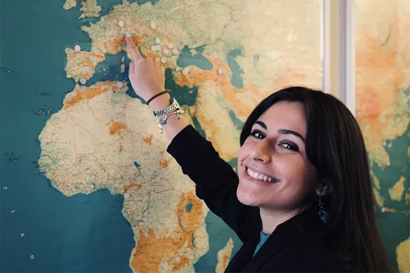jeune femme souriante devant un planisph&egrave;re